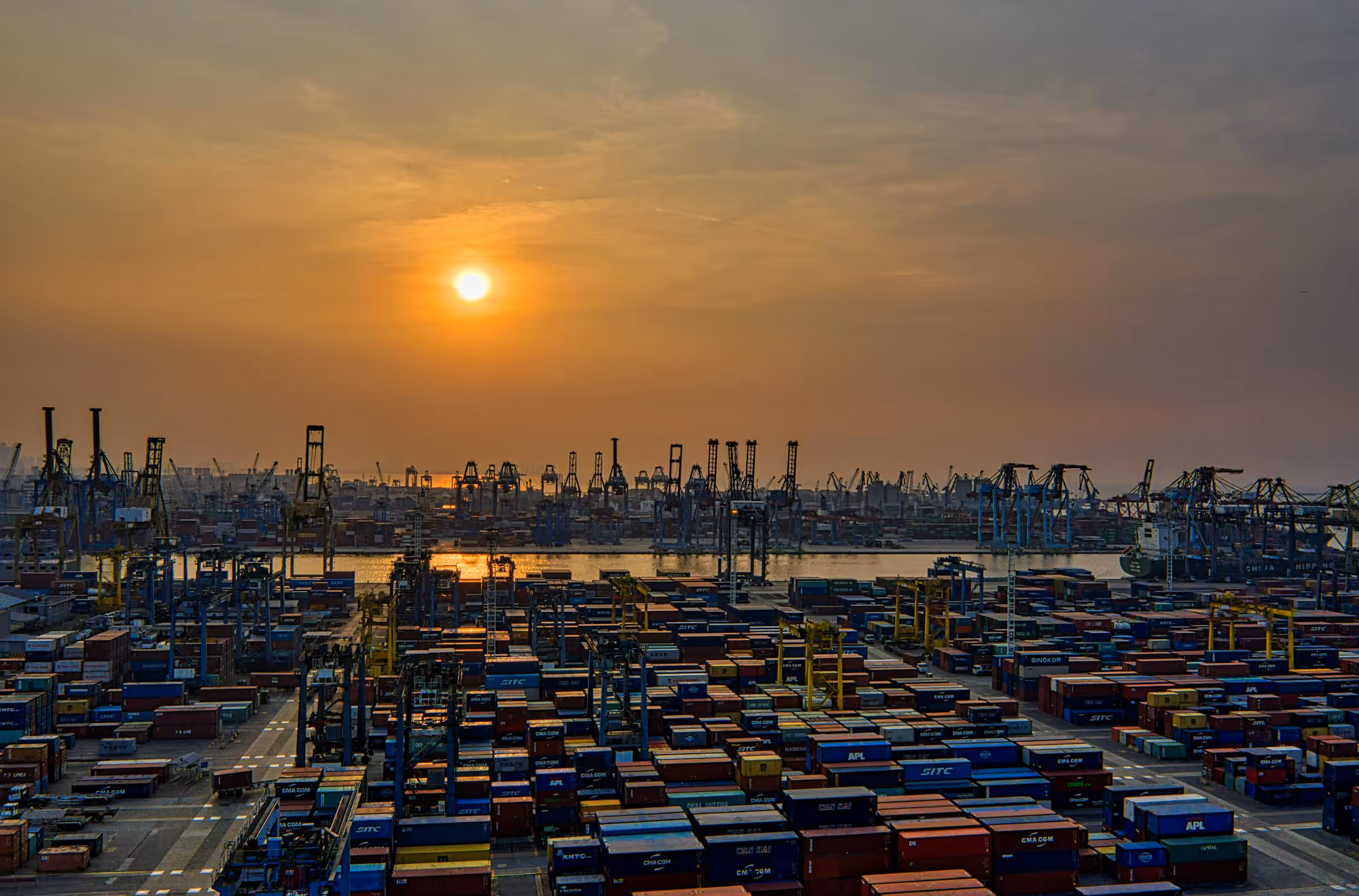 Container port gantry cranes at sunset